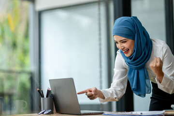 A woman wearing a blue scarf is pointing at a laptop screen