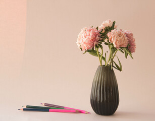 Bouquet of asters flowers in vase and colored pencils . Pink  garden flowers on pastel background.