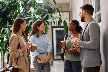 Multiracial group of happy coworkers communicating in office lobby.