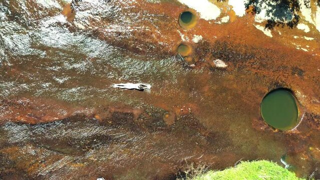 Aerial view of the natural reserve of wells, Las Gachas while a girl slide in the water in Guadalupe, Santander, Colombia, South America.
