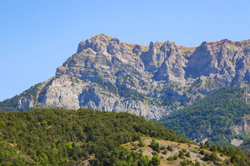 Fototapeta premium Mountain above the lake of Serre-Ponçon in the French Alps is a dammed artificial reservoir gathering the water of the Durance river
