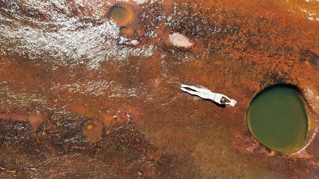 Aerial view of the natural reserve of wells, Las Gachas while a girl slide in the water in Guadalupe, Santander, Colombia, South America.
