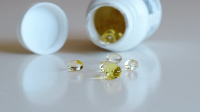 Fish oil omega 3 supplements spilling out of a packer bottle on a white background