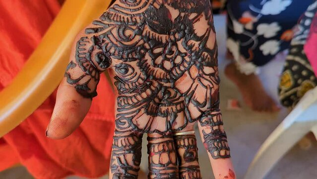 An Indian woman is showing a beautiful henna tattoo design on her hand on her wedding day
