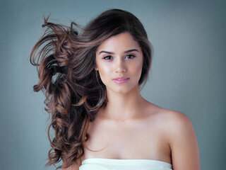 Woman, blue background or portrait with wave in hair care and makeup, aesthetics with facial glow....