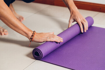 Young man rolling up her exercise mat after a yoga class.