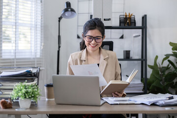 Young Asian woman reviewing documents at office desk. Concept of business analysis and productivity