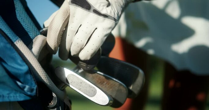 Close-up shot of a young female professional golfers glove hand selecting a club to play from a golf bag. Sports equipment for playing golf. Country Club.