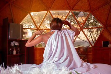 lifestyle: woman waking up in the morning stretches while contemplating beautiful landscape out the window