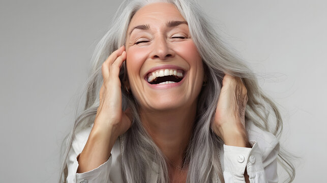 Beautiful 60 years old beautiful elderly senior model woman with grey hair laughing and smiling. isolated on white background