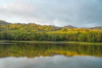 Beautiful nature lake and forest , Jet Khot Nature Study Centre lake and forest in Thailand. Beautiful view of a golden sun shining over a reflective lake under a cloudy sky after sunrise
