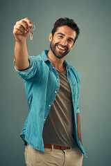 Smile, portrait and happy man with key in studio for real estate, property or new home owner on...