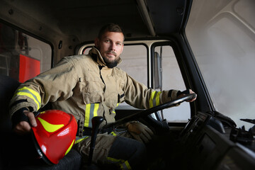 Firefighter in uniform with helmet driving modern fire truck