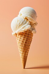 A vanilla ice cream cone with two scoops of ice cream on a soft orange pastel background. Vanilla ice cream in a wafer cup.