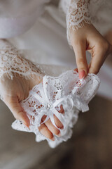 A woman is holding a white lace train with a bow on it. The train is being used as a wedding accessory