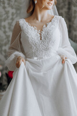 A woman in a white dress with a bow on her waist. She is holding the dress up to her body