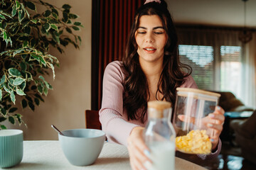 One young caucasian woman is eating corn flex breakfast at home before work	