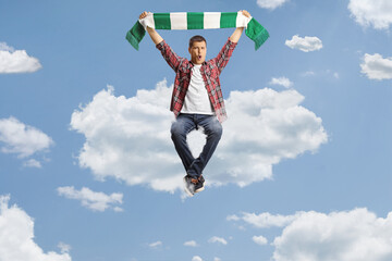 Happy yougn man sitting on a cloud and cheering