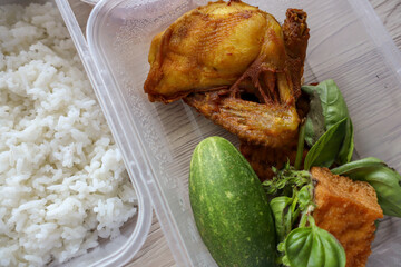 Traditional Indonesian meal featuring fried chicken, tofu, tempeh, fresh vegetables, white rice, sambal pecel, and unsweetened tea