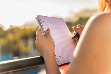 Woman Writing in Notebook Outdoors - Focused Study Session at Sunset