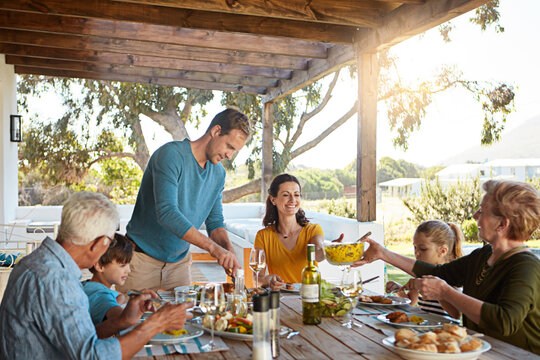 Big family, eating and lunch with food outdoor on patio with conversation, bonding or healthy meal in summer. Parents, grandparents and kids at dining table in backyard of home with talking and happy