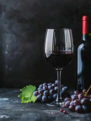 Obraz premium A glass of red wine with a bottle and grapes on a dark background, providing copy space on the top and bottom