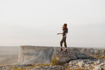 Woman enjoying serenity and freedom on top of desert rock with arms outstretched in travel adventure concept