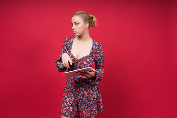 A woman in a purple floral dress is holding a tablet computer