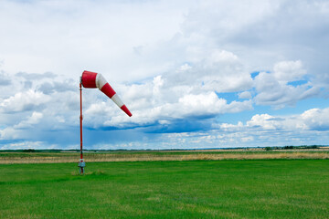 Weather vane in the airfield with grass and dramatic cloudy sky.