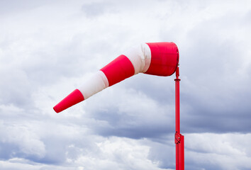 Red and white weather vane and dramatic cloudy sky.