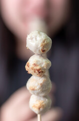 Woman happily eating meatball on blurred background