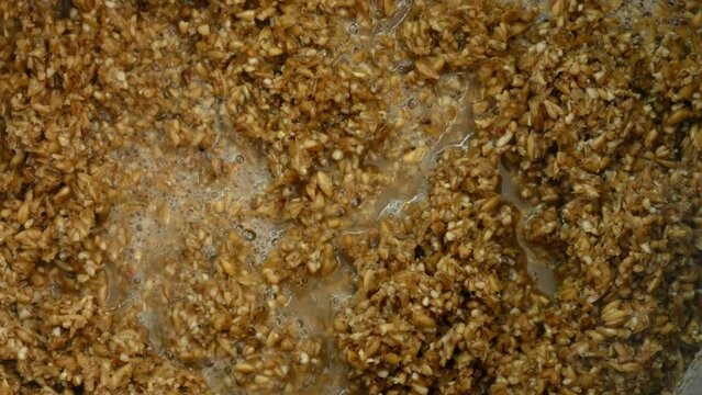Malt mash is stirred with a large spoon during brewing