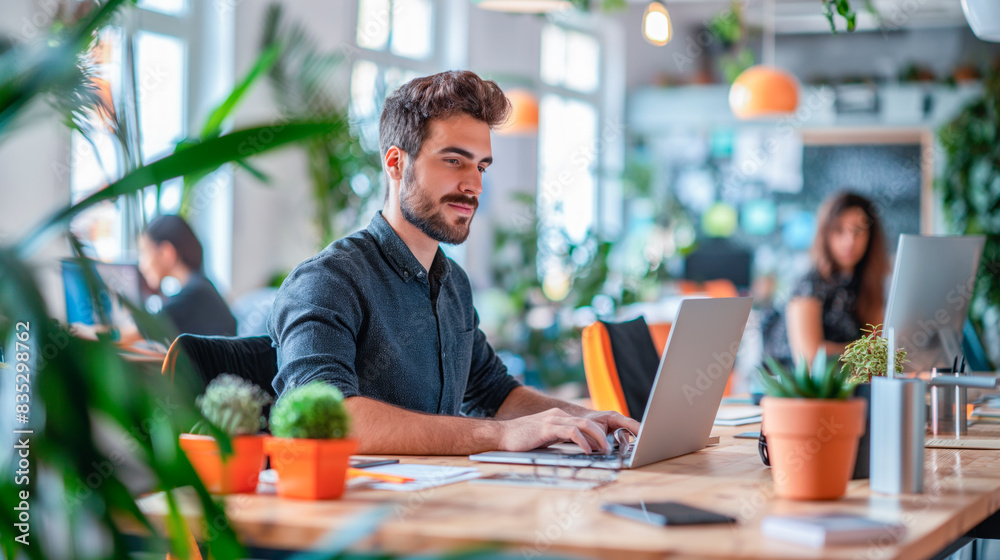 Poster a man typing on a laptop in a modern office setting, surrounded by plants, embodying the concept of 