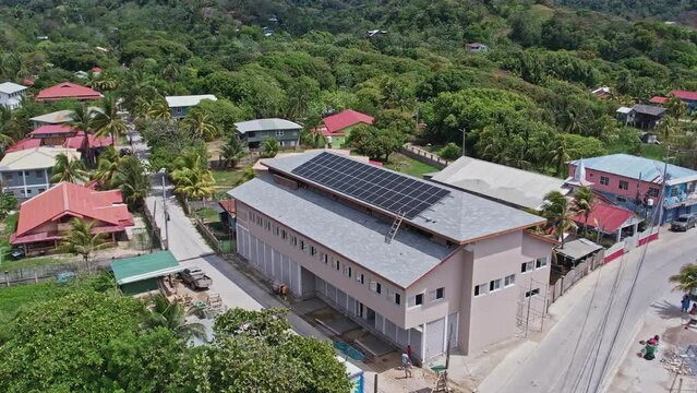 drone footage of solar panels on the roof of a building in roatan honduras
