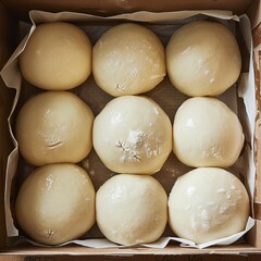 Uncooked frozen dough balls covered in flour in a cardboard box.
