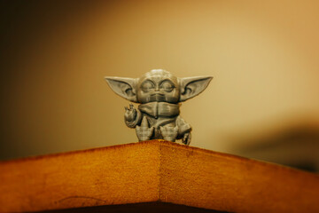 Naklejka premium Madrid, Spain 7 May 2024 Din Grogu, Star wars toy hero made of recycling plastic isolated on yellow background. Happy baby Yoda from Disney series.