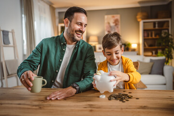 Father and son save money coins together at piggy bank at home