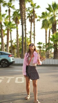 Woman enjoys a beautiful sunny day surrounded by palm trees, feeling carefree and relaxed