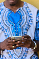 African American Teenager in Traditional Sudanese Attire Engaged with Smartphone