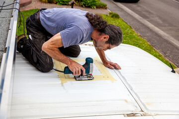 DIY Camper Jumper van conversion. new window outside. cutting with an electric jigsaw. preparation for installing a top window. 