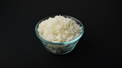 a small serving of basmati rice in a glass bowl on a black background