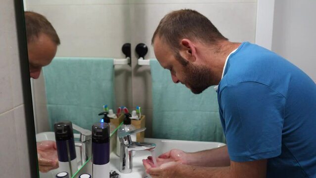 video of man in bathroom washing his face in the morning