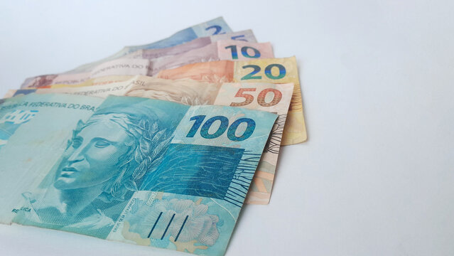 Notas de real brasileiro espalhadas exibindo valores de 2 a 100 reais