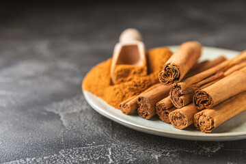 Ceylon cinnamon.Cinnamon sticks on a textured wooden background. Cinnamon roll and powder. Spicy spice for baking, desserts and drinks. Fragrant ground cinnamon. Close-up. Place for text. copy space