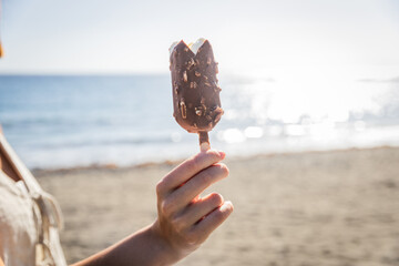 Close up of a stick of ice cream held by a girl on a beach