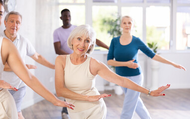 Dynamic mature attendees of dancing courses training Hip-hop dance poses in dancehall