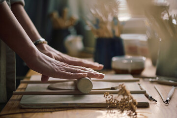 Closeup shot of hands of unrecognizable female artisan rolling out piece of clay, copy space