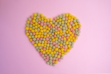 Heart of sweets scattered. Sweet multi-colored flakes on a colored background. Fast food concept, space for text