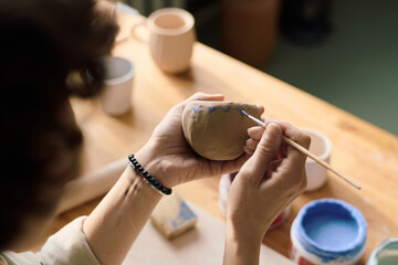 High angle view closeup of unrecognizable woman coloring handmade ceramic vessel