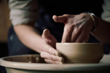 Hands of unrecognizable female artisan shaping bowl on potters wheel, closeup shot